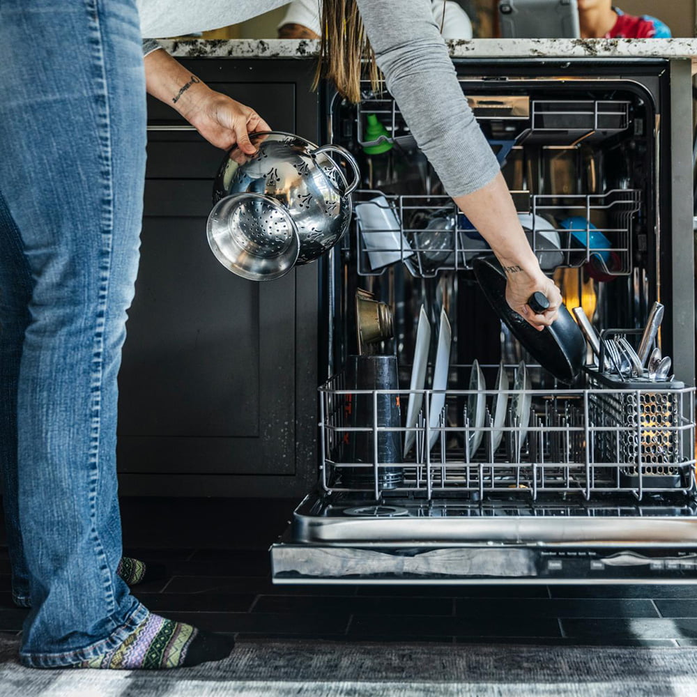 Loading dishwasher with precision for optimal cleaning results.