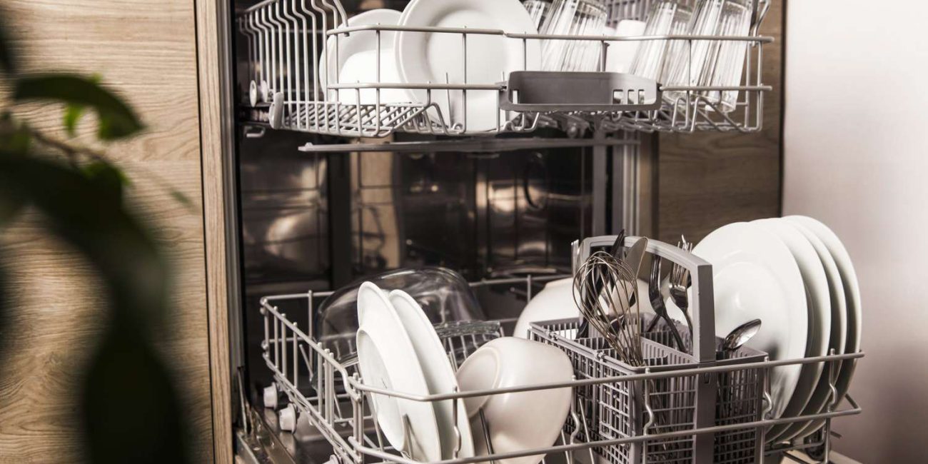 Open dishwasher filled with clean plates and kitchen items