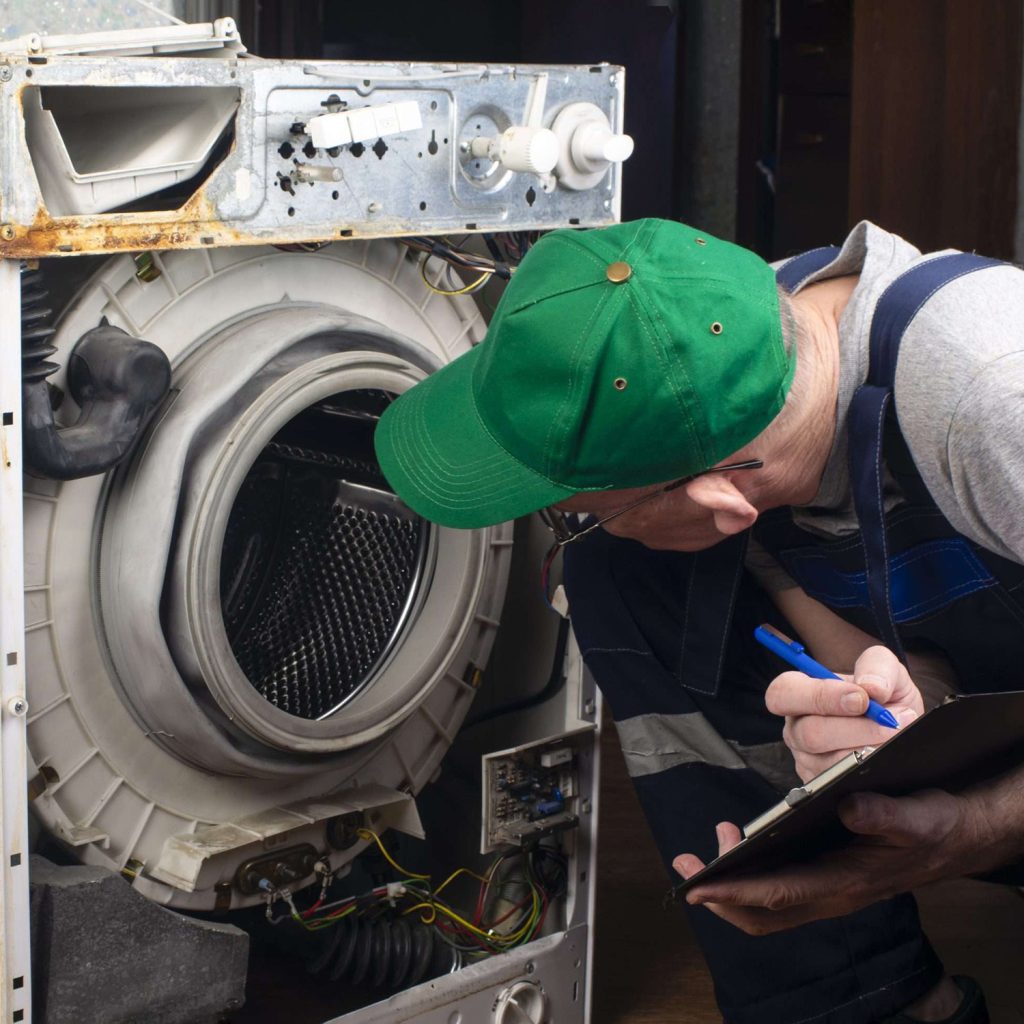 White goods repair technician noting down details on a clipboard during a service visit.